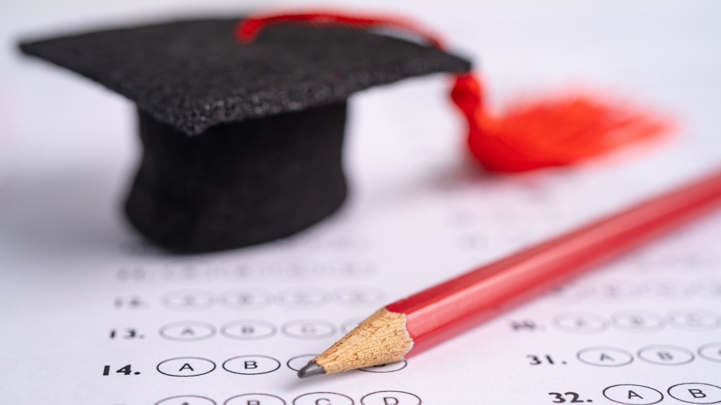 Czapka żaka, ołówek i arkusz egzaminacyjny